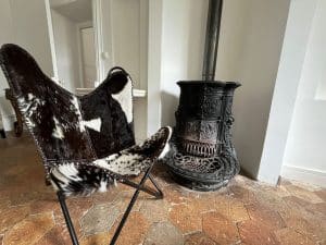 Poêle à bois en fonte et fauteuil en peau, sol en tomettes — Villa Hoffman, location saisonnière à Épernon